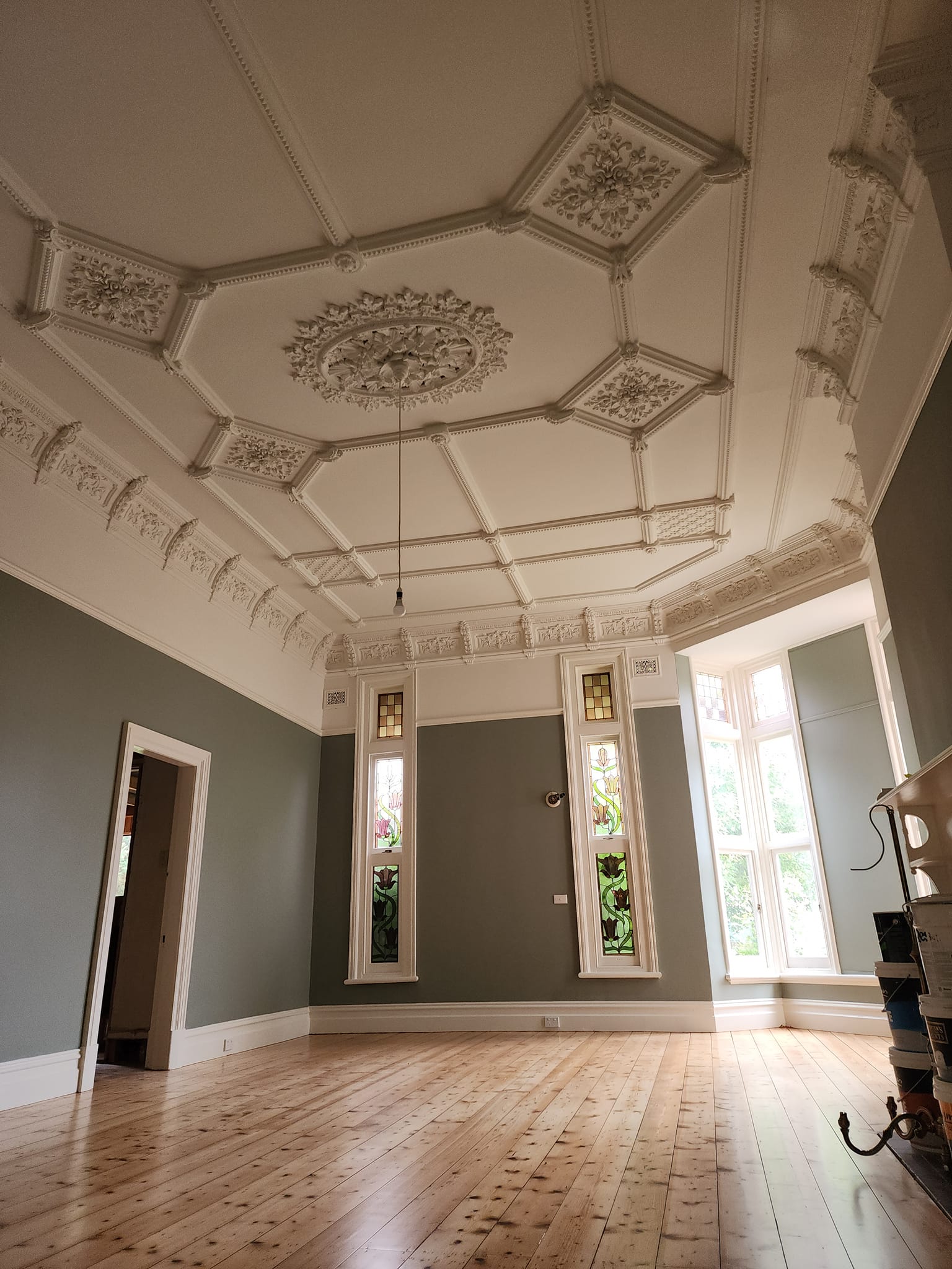 Octagonal panelled heritage ceiling with a floral ceiling rose, sage walls and stained glass