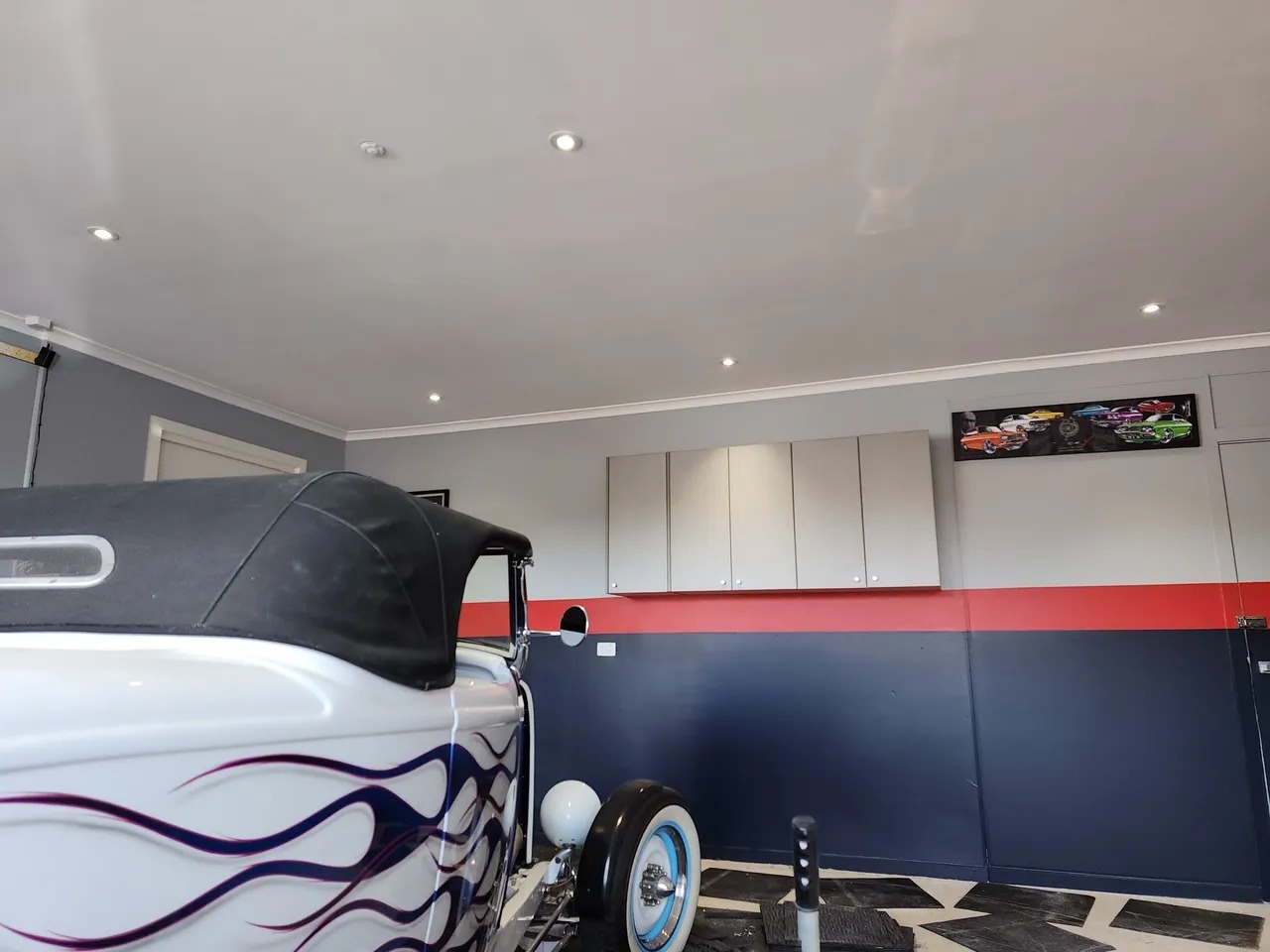 Smooth garage ceiling with recessed downlights above a hot rod