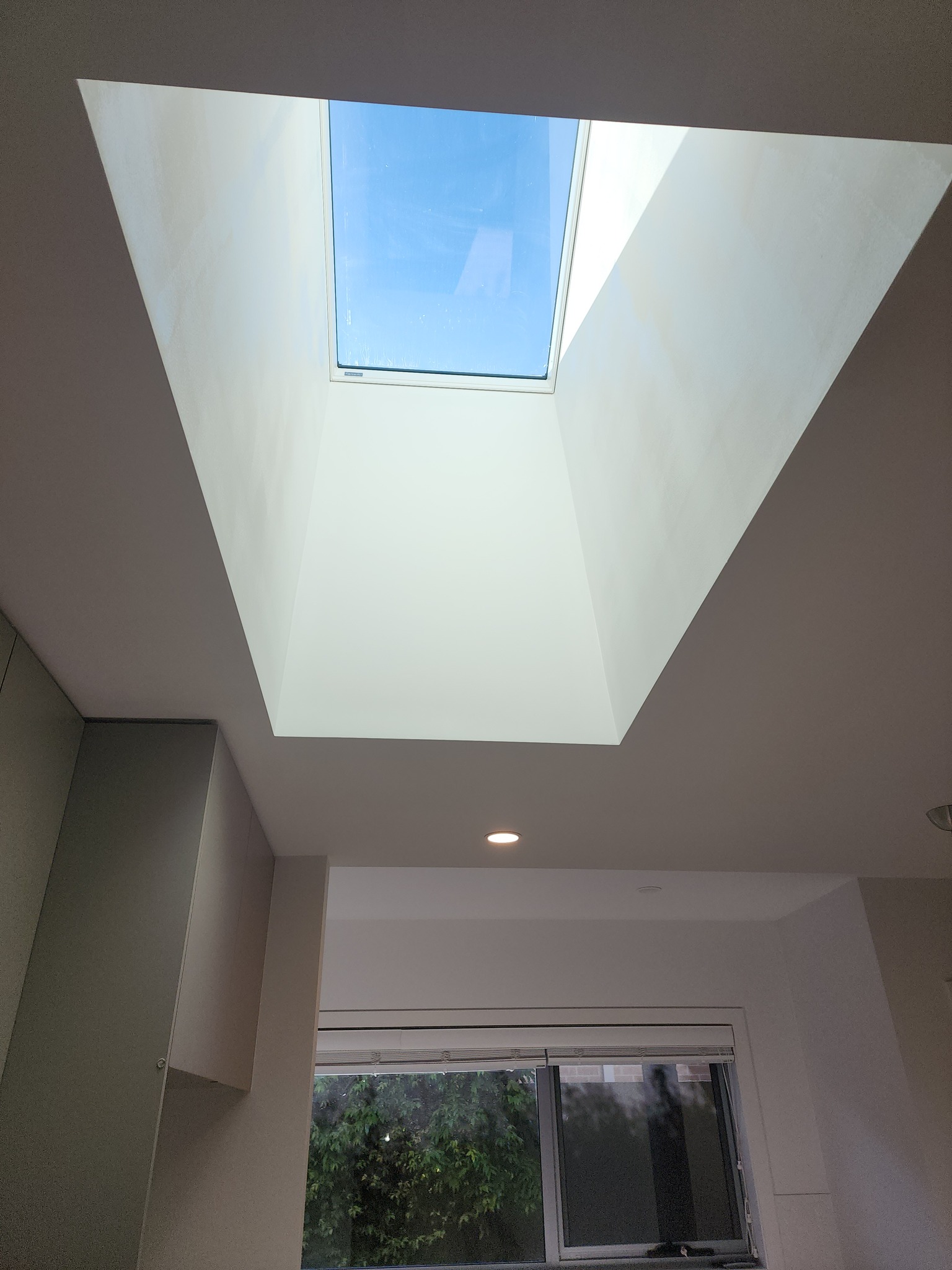 Clean modern plastered ceiling void around a raked skylight